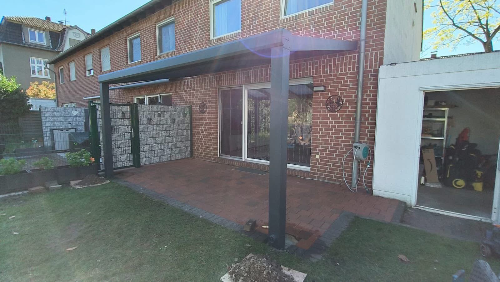 Open veranda met aluminium staanders boven een bestraat terras aan de achtergevel